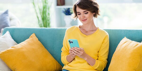 Junge Frau nutzt in ihrer Wohnung die App der NEUE LÜBECKER